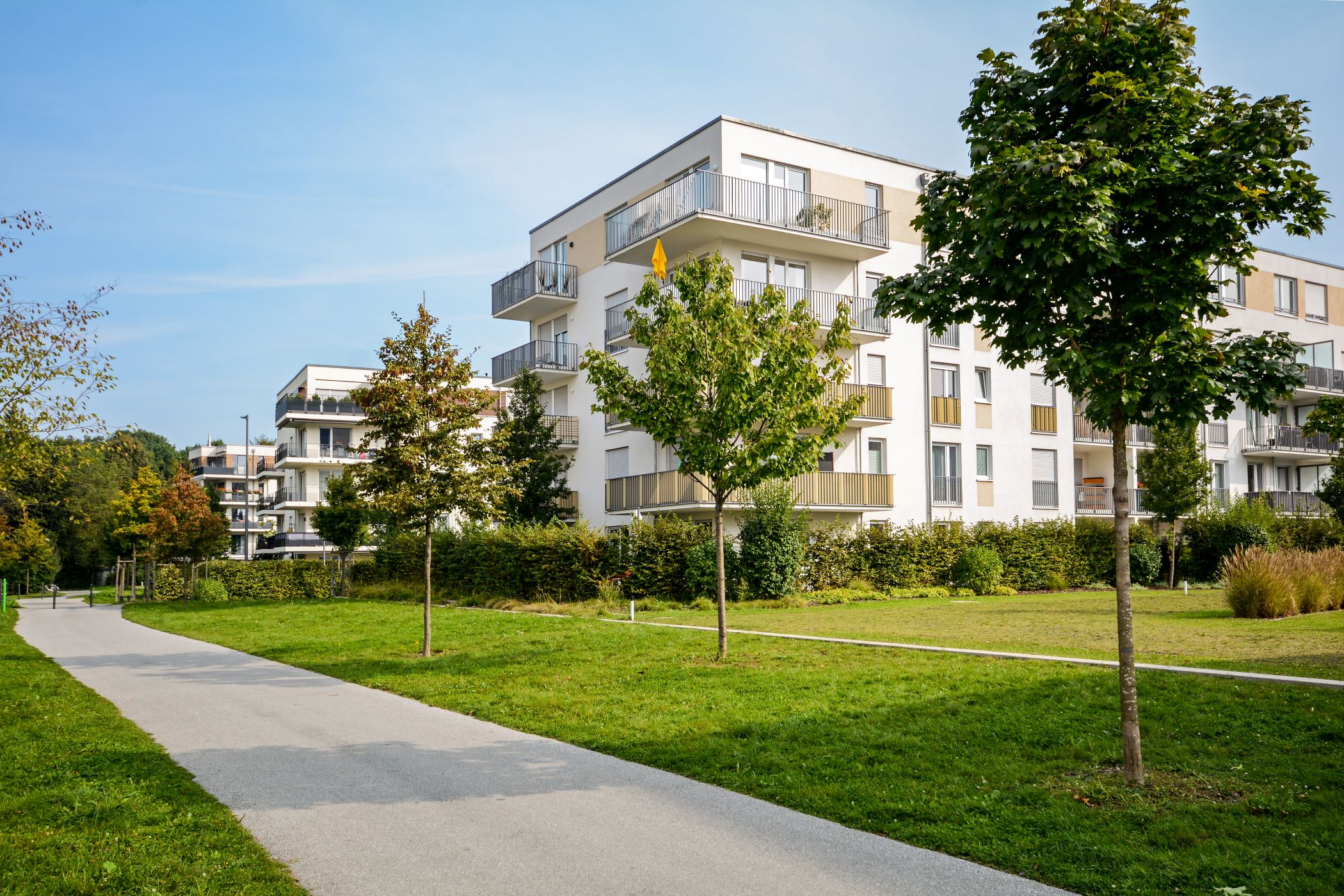 Boligområde med hvite boligblokker og grøntareal med beplantning