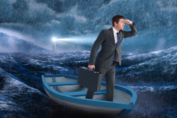 Man standing in boat on rough seas, looking for a light.